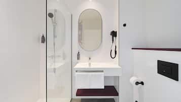 A modern bathroom with a glass shower enclosure, a white sink with a mirror, and a red towel rack.