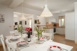 Een eethoek met witte meubels, een gedekte tafel en een keuken op de achtergrond.