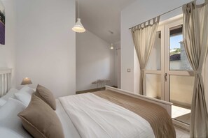 Een slaapkamer met een bed, een raam met gordijnen, een bedlampje en een radiator.