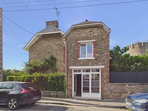 Ein Steinhaus mit kleinem Fenster und einer Tür, neben einer gepflasterten Straße.
