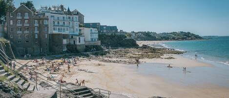 Un hôtel situé sur la côte, avec plusieurs étages, une plage en arrière-plan et une côte rocheuse.