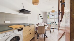 Uma cozinha compacta com máquina de lavar, bancada de madeira e área de refeições com cadeiras e mesa.