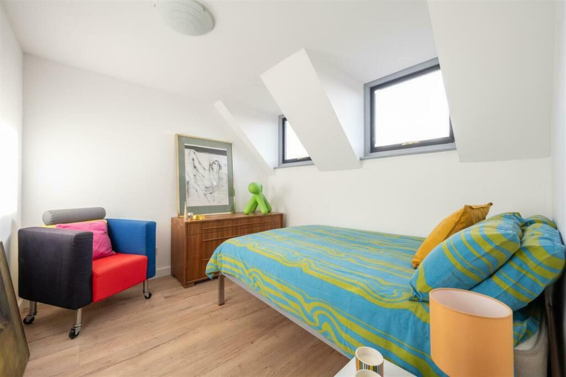 Een slaapkamer met een bed, een bureau, een stoel en een raam.