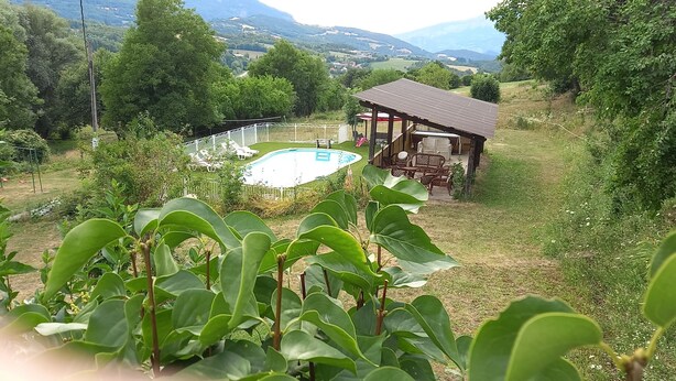 A pool surrounded by a white fence, a wooden gazebo, and lush greenery. - A quiet and spacious country-style group lodging with a pool, (Ubaye-Serre-Ponçon)