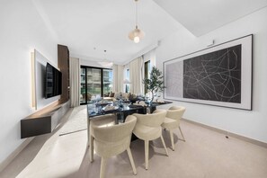 A modern dining area with a glass table, chairs, and a large abstract painting on the wall. - StayShort - Stunning 2-Bedroom Apartment in Mina Rashid That Sleeps 6! (Dubai)