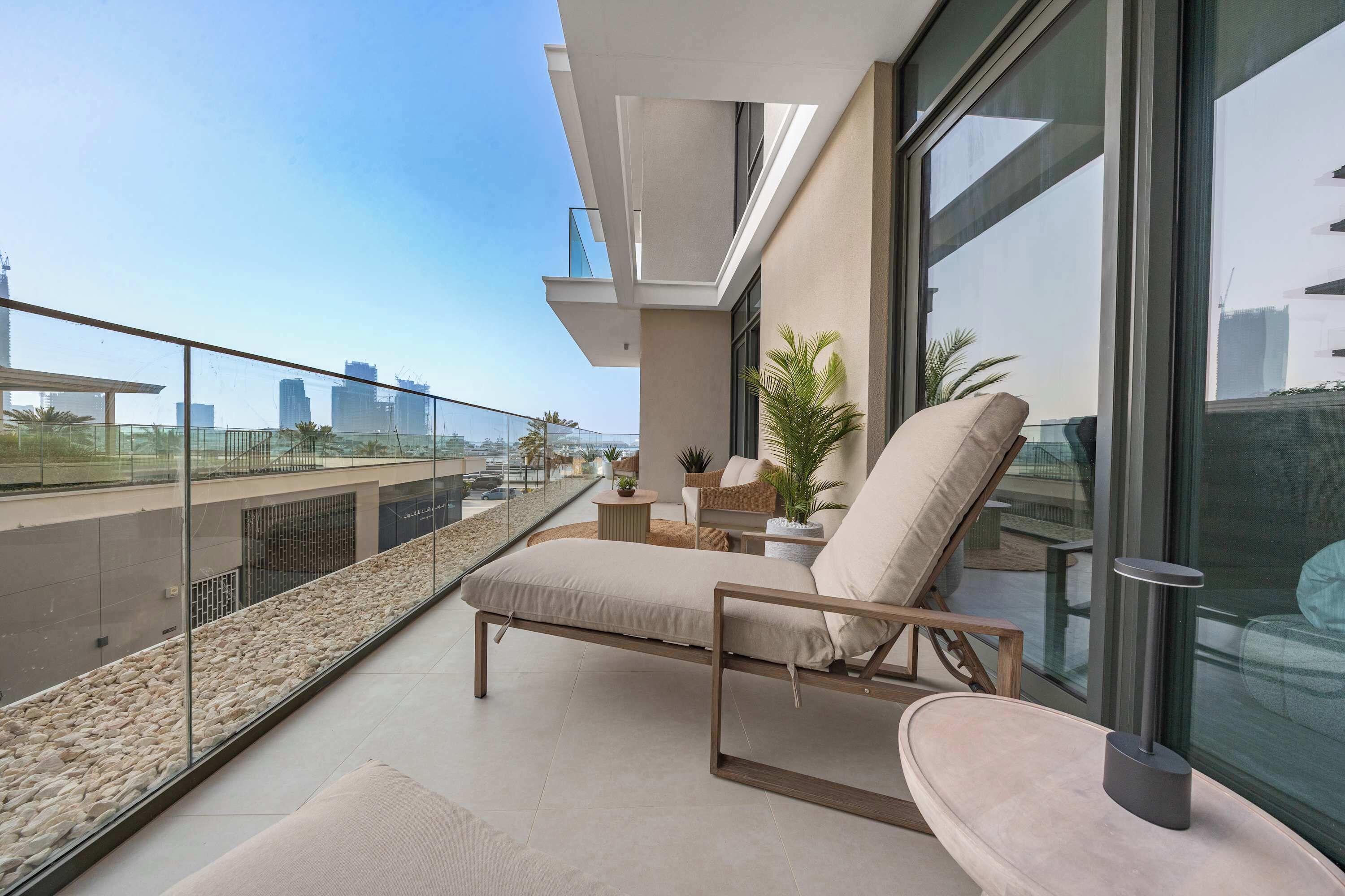 A balcony with a lounge chair, a small table, and a potted plant.