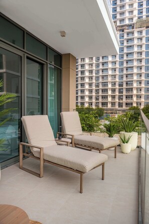 A balcony with two lounge chairs and a potted plant. - StayShort - Stunning 2-Bedroom Apartment in Mina Rashid That Sleeps 6! (Dubai)