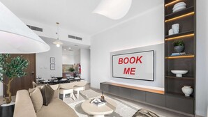 A modern living area with a sofa, coffee table, and a 'BOOK ME' sign on the wall. - StayShort - Stunning 2-Bedroom Apartment in Mina Rashid That Sleeps 6! (Dubai)