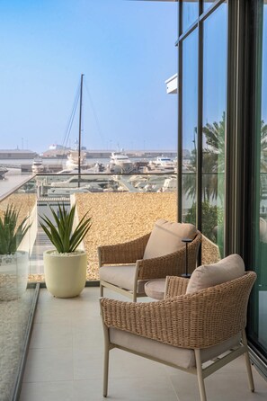 A balcony with wicker furniture, a potted plant, and a view of a marina with boats. - StayShort - Stunning 2-Bedroom Apartment in Mina Rashid That Sleeps 6! (Dubai)