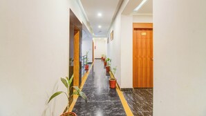 Un pasillo con plantas en macetas, una puerta de madera y un suelo de mármol.