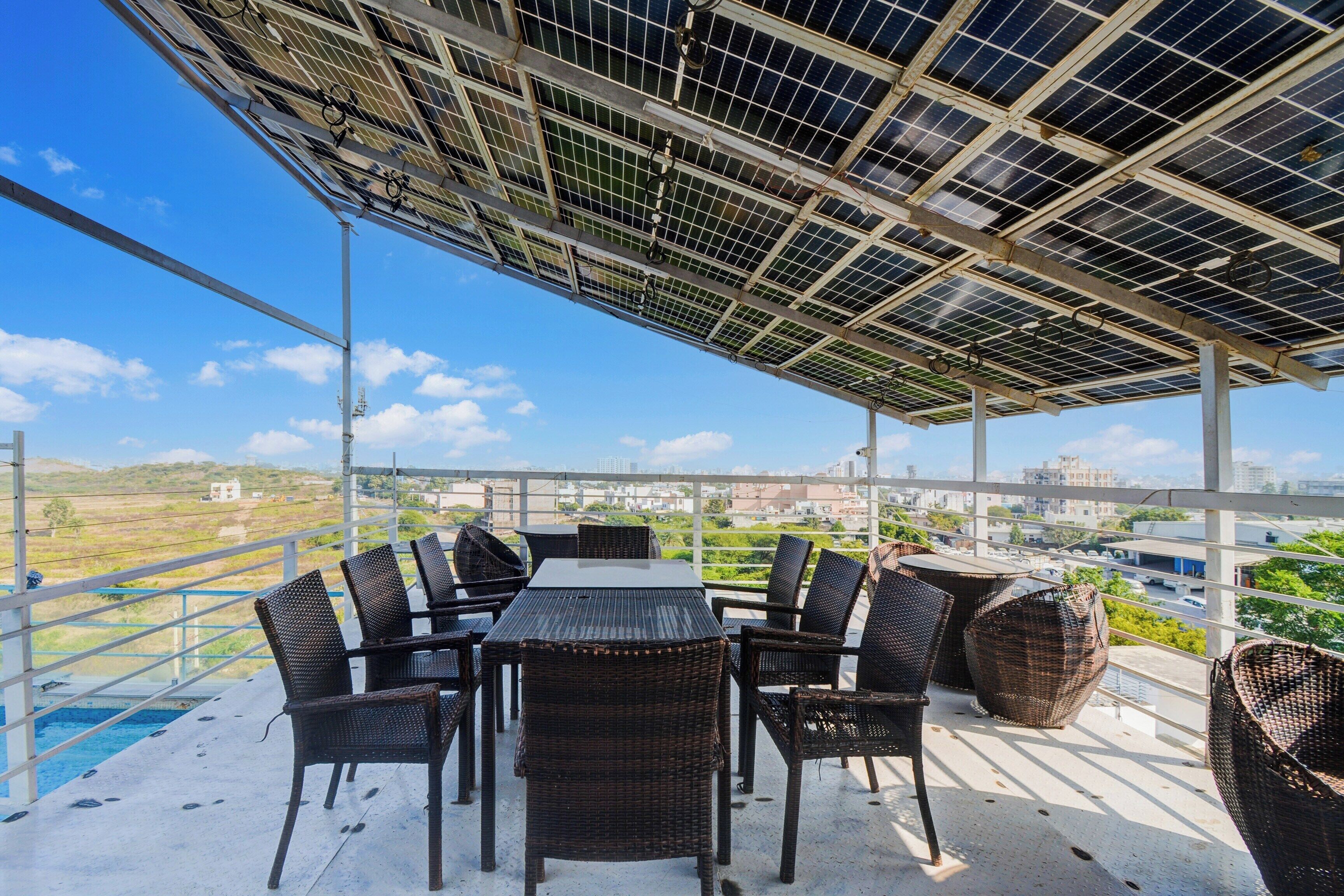 A rooftop terrace with a table and chairs, solar panels, and a view of the city.