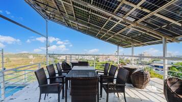 A rooftop terrace with a table and chairs, solar panels, and a view of the city.