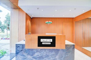 A reception desk with a sign indicating 'Reception' and 'PALETTE Company-Serviced.' - Palette Goverdhan Villas (Udaipur)