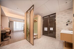 Quarto de hotel moderno com escrivaninha, cadeira e uma janela grande.