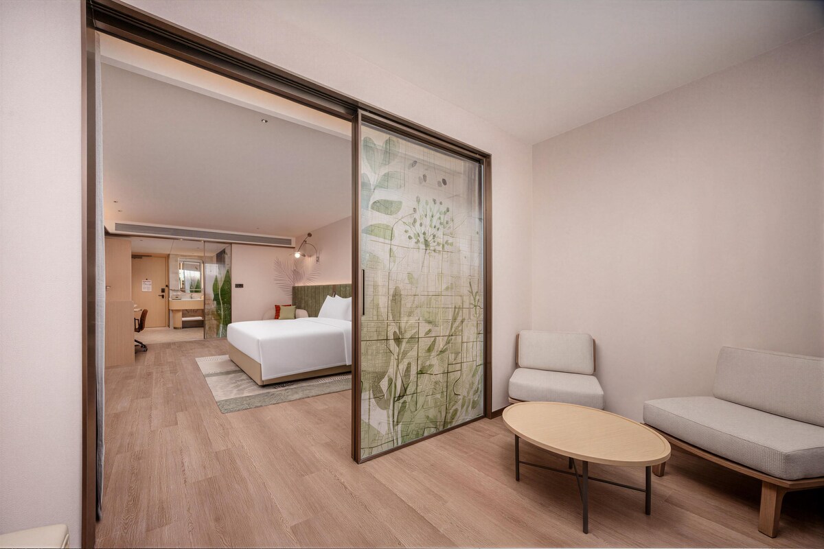 Ein Hotelzimmer mit Bett, einer Sitzecke mit Tisch und einer Schiebetür zu einem Badezimmer.