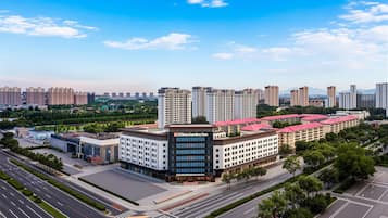 A multi-story hotel with a red roof, surrounded by a well-maintained urban environment with roads and greenery.