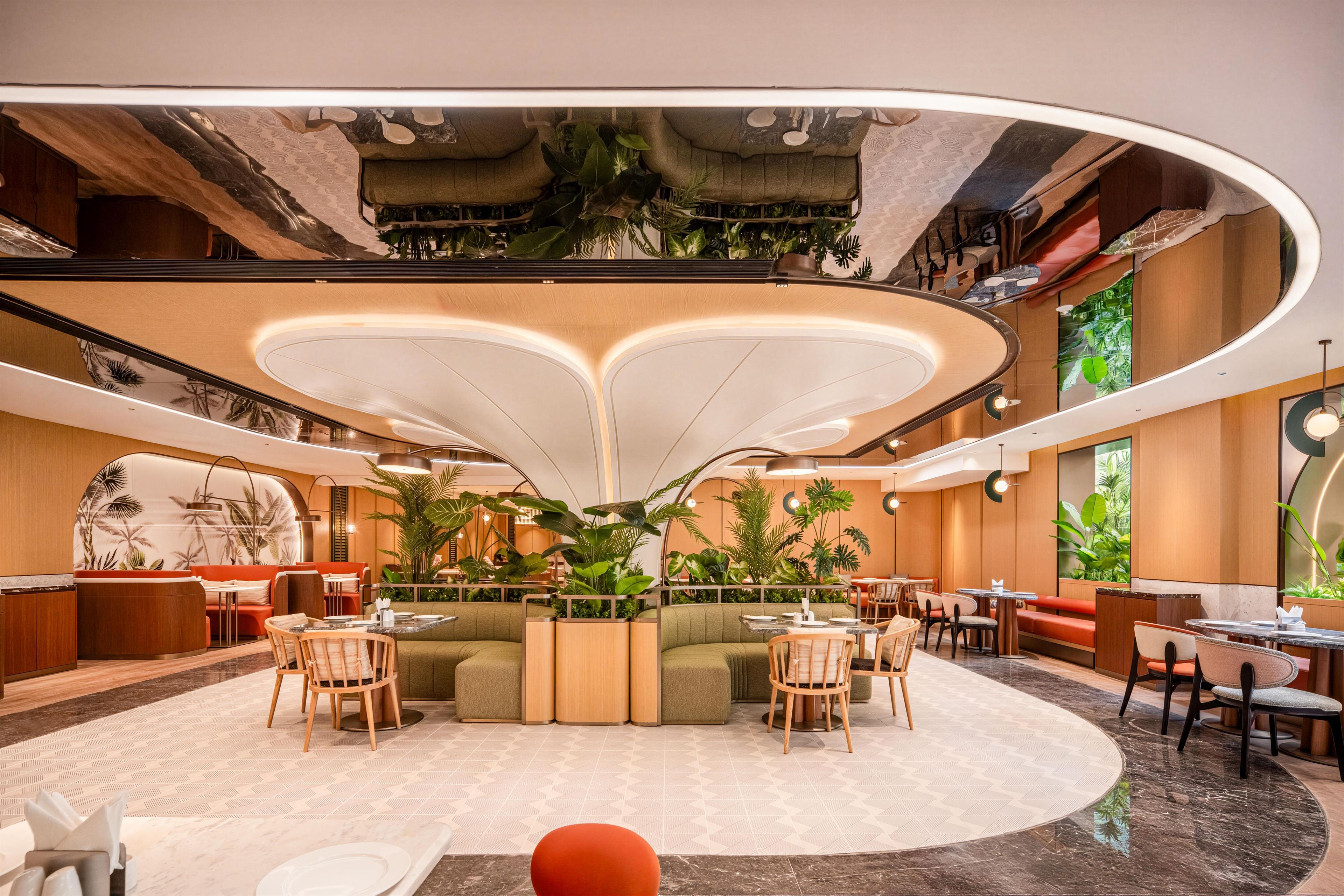 Un intérieur moderne avec un espace salon central, plusieurs tables à manger et de nombreuses plantes d’intérieur.