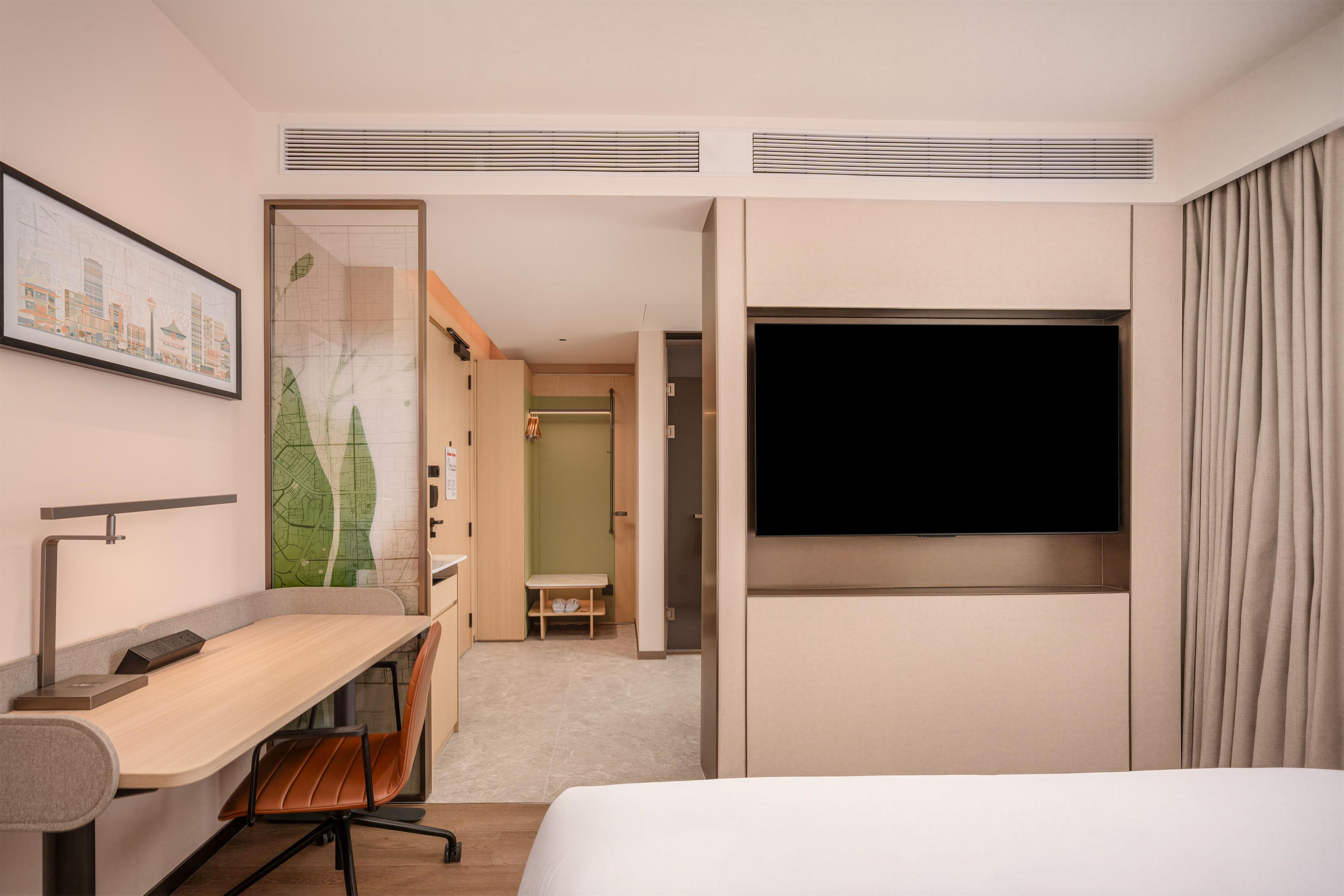 Una habitación de hotel con una cama, un escritorio, una silla, un televisor y un armario.
