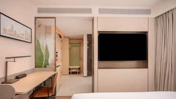 Una habitación de hotel con una cama, un escritorio, una silla, un televisor y un armario.