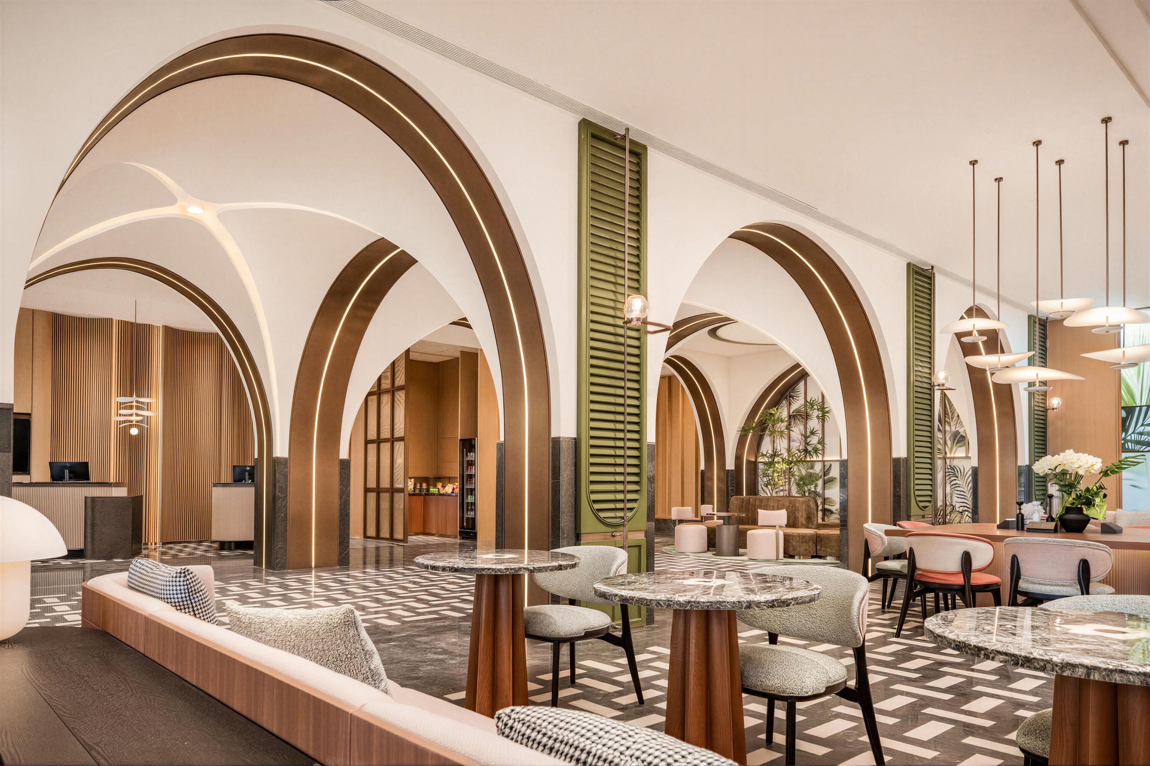 A spacious lobby with high arched ceilings, a reception desk, seating areas, and a bar.