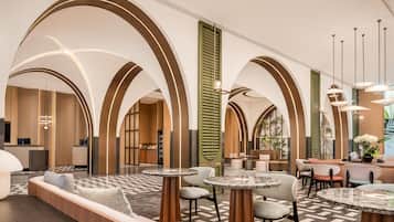 A spacious lobby with high arched ceilings, a reception desk, seating areas, and a bar.