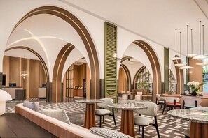 Un vestíbulo amplio con techos altos en arco, una recepción, zonas de estar y un bar.