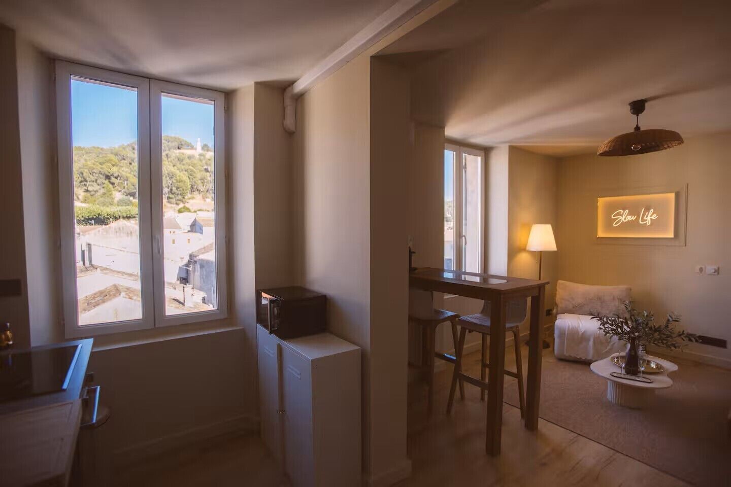 A room with a dining area, a bed, a lamp, and a view of the outdoors.