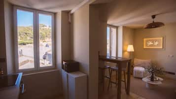 A room with a dining area, a bed, a lamp, and a view of the outdoors.