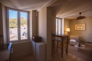 A room with a dining area, a bed, a lamp, and a view of the outdoors.