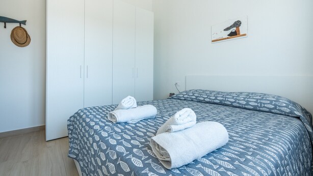 Ein Schlafzimmer mit einem Bett, einem Kleiderschrank und einem an der Wand befestigten Regal mit einem Bild.