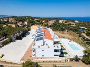 Un bâtiment moderne avec une longue rangée de pièces, une piscine et un parking.