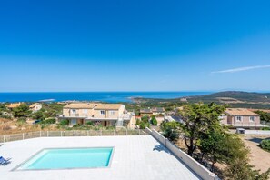 Ein Wohngebiet mit Schwimmbad, Häusern mit Solaranlagen und Blick auf das Meer.