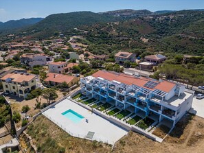 A residential area with a modern building featuring a rooftop pool and multiple balconies.