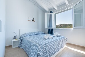 Ein Schlafzimmer mit einem Bett, einem Nachttisch, einem Fenster mit Aussicht und einem Wandbild.