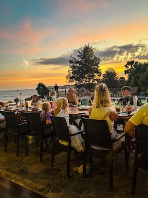 An outdoor dining area with tables and chairs, overlooking a body of water during sunset. - Thaulle Luxury Boutique & Social Club  (Kirinda)
