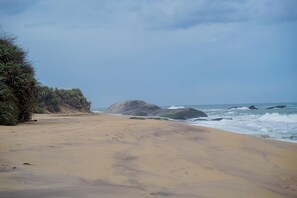 A sandy beach with large rocks and waves in the background. - Thaulle Luxury Boutique & Social Club  (Kirinda)