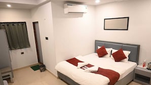 A hotel room with a bed, a nightstand, an air conditioning unit, a window with curtains, and a door. - HOTEL K11 (Haldwani)