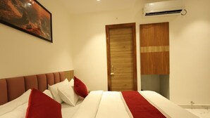 A hotel room with a bed, a wooden wardrobe, and a wall-mounted air conditioning unit. - HOTEL K11 (Haldwani)