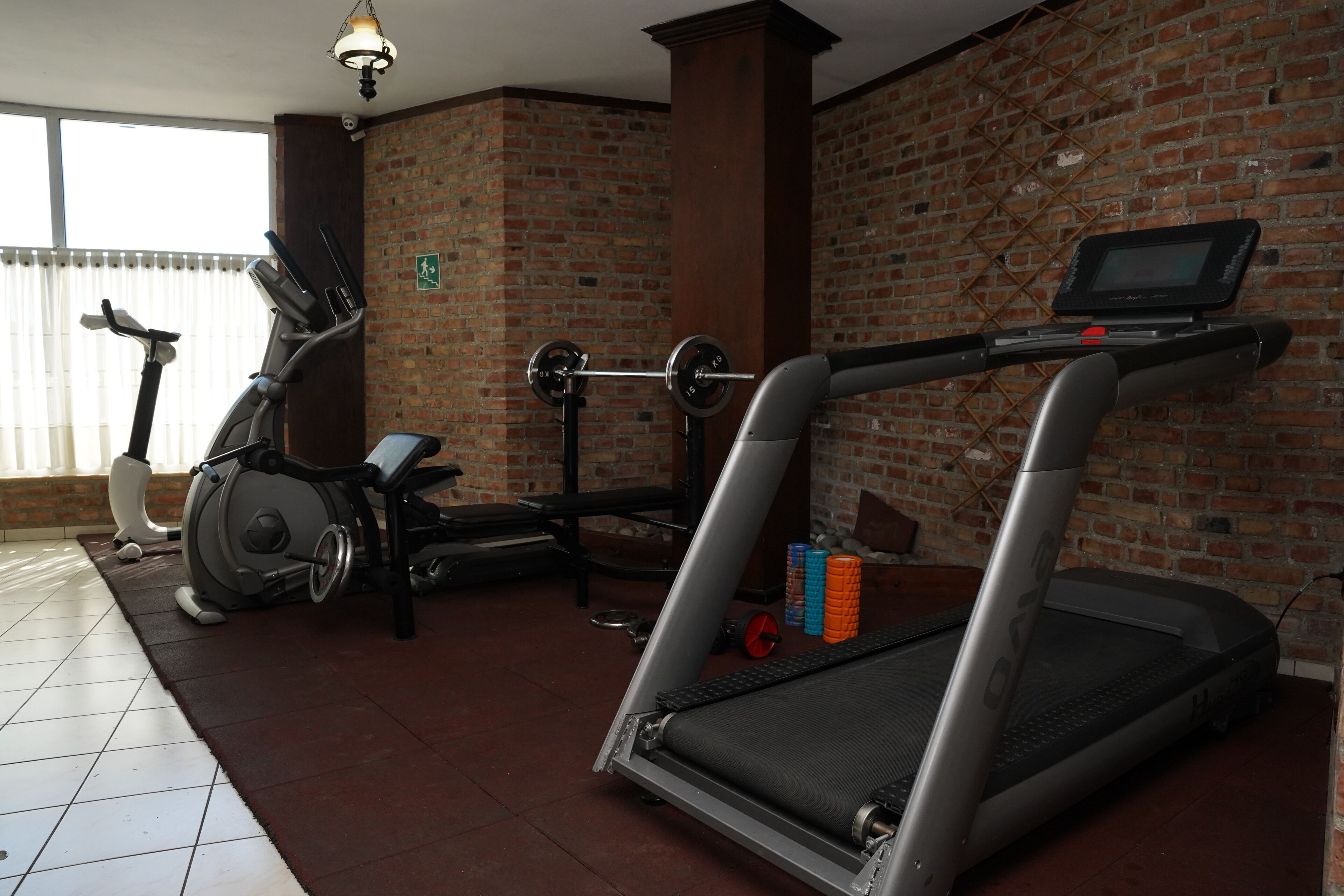 A gym with exercise equipment including treadmills, a stationary bike, and a weight bench.
