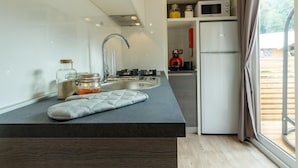 Une cuisine moderne dotée d’un îlot central intégré, d’appareils électroménagers en acier inoxydable et offrant une vue sur l’extérieur.