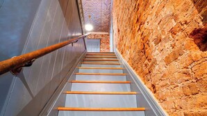Eine Treppe mit hölzernen Geländern, einer Backsteinwand an der Seite und einer bemalten Decke.