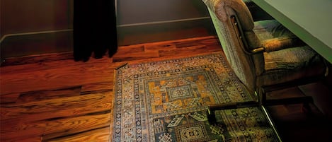 Una habitación con ventana, escritorio, silla y alfombra estampada.