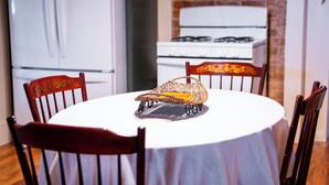 Ein runder Esstisch mit weißer Tischdecke, umgeben von vier Holzsesseln mit geschnitzten Verzierungen.