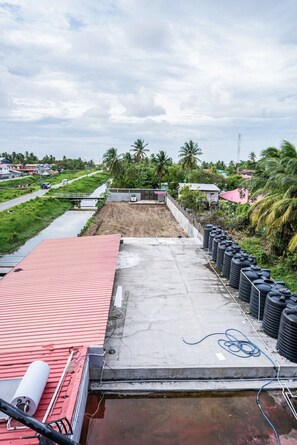 A rooftop with a red roof, a concrete floor, and several black water tanks lined up on one side.