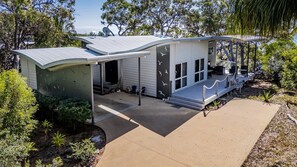 A modern house with a covered porch, satellite dishes, and a landscaped garden. - GULL COTTAGE - SUNRISE AT 1770 (AGNES WATER)