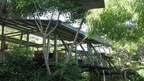 Ein Baumhaus mit Metallgerüst, Holzterrasse und umgebendem Grün.