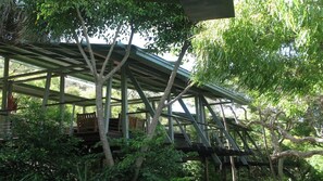 Ein Baumhaus mit Metallgerüst, Holzterrasse und umgebendem Grün.