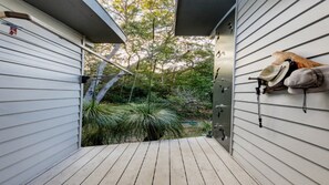 A wooden deck with a view of a garden and a building with a white exterior. - GULL COTTAGE - SUNRISE AT 1770 (AGNES WATER)