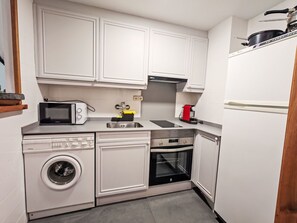 Eine kompakte Küche mit Mikrowelle, Toaster, Spüle, Herd, Backofen und Waschmaschine.