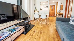 Una sala de estar moderna con un televisor de pantalla plana, una chimenea, un comedor con mesa y sillas, y un sofá.